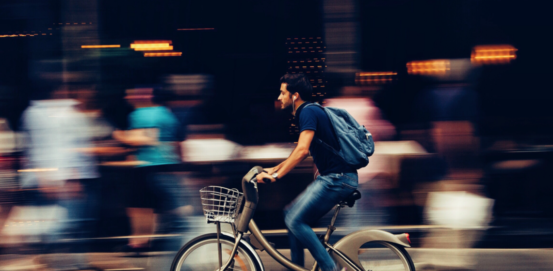 Motion blur shot of a man riding bike past pedestrians