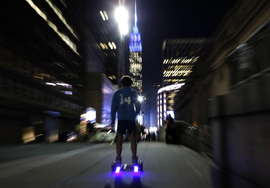 Person riding a battery-boosted mobility device through a city at night