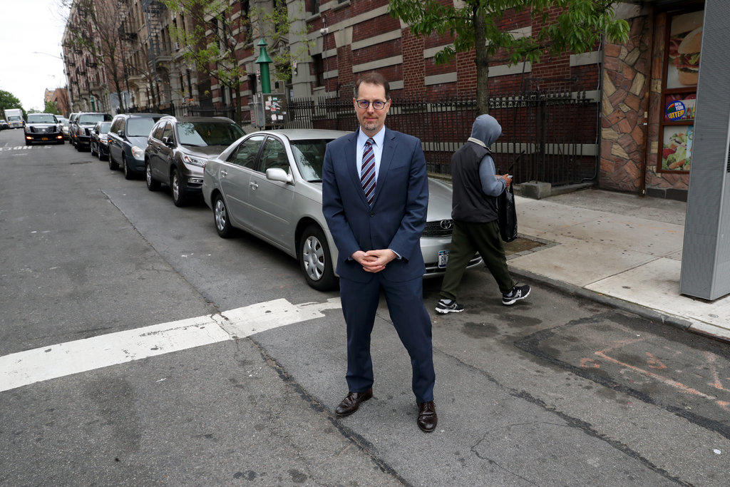 A man standing in front of a parked car