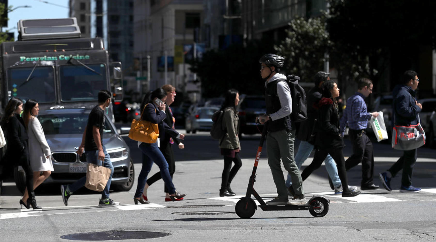 Person on scooter and pedestrians crossing a street