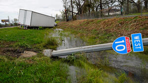 An truck and road sign lay by the side of the road after a storm